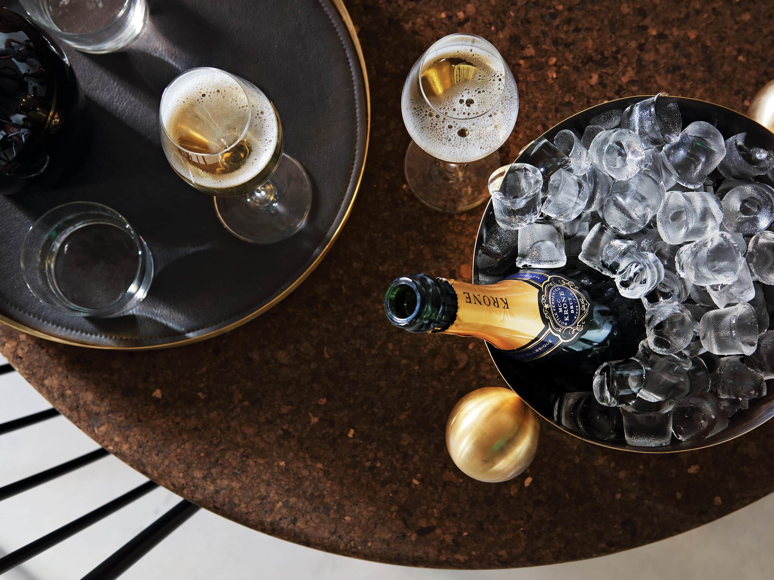 Krone bottle in an ice bucket with two full glasses alongside. Krone bottle in an ice bucket with two full glasses alongside.