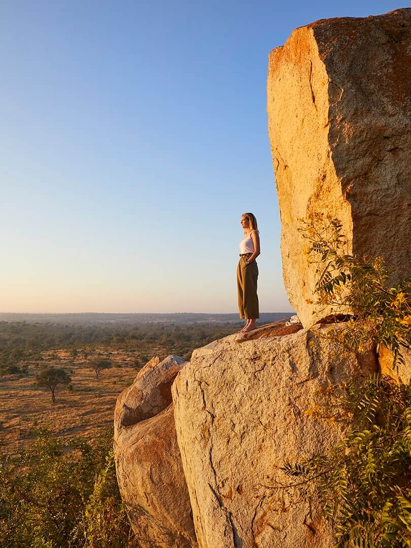 Woman standing on a cliff edge looking out across the plains at Londolozi, South Africa. Photograph by Elsa Young. Woman standing on a cliff edge looking out across the plains at Londolozi, South Africa. Photograph by Elsa Young.