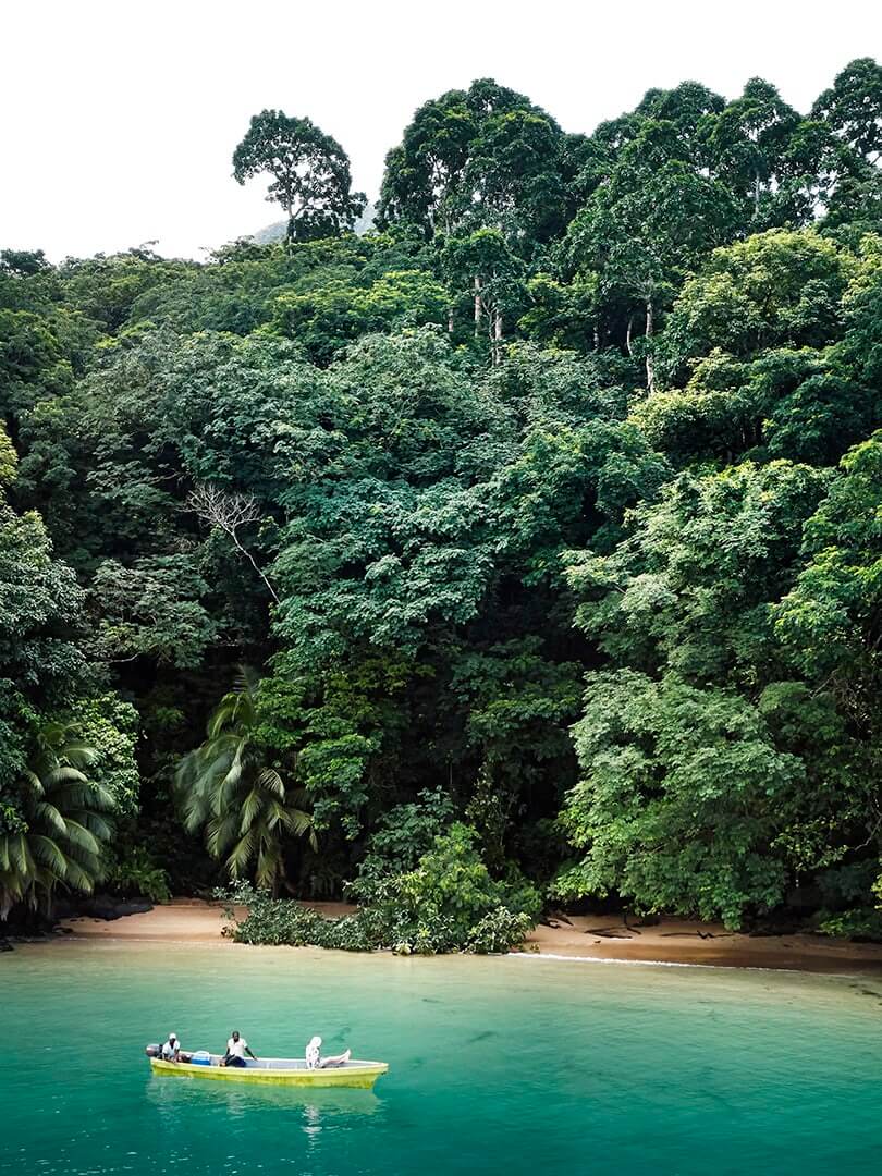 Small motorboat on the ocean in a bay surrounded by jungle, Principe. Small motorboat on the ocean in a bay surrounded by jungle, Principe.
