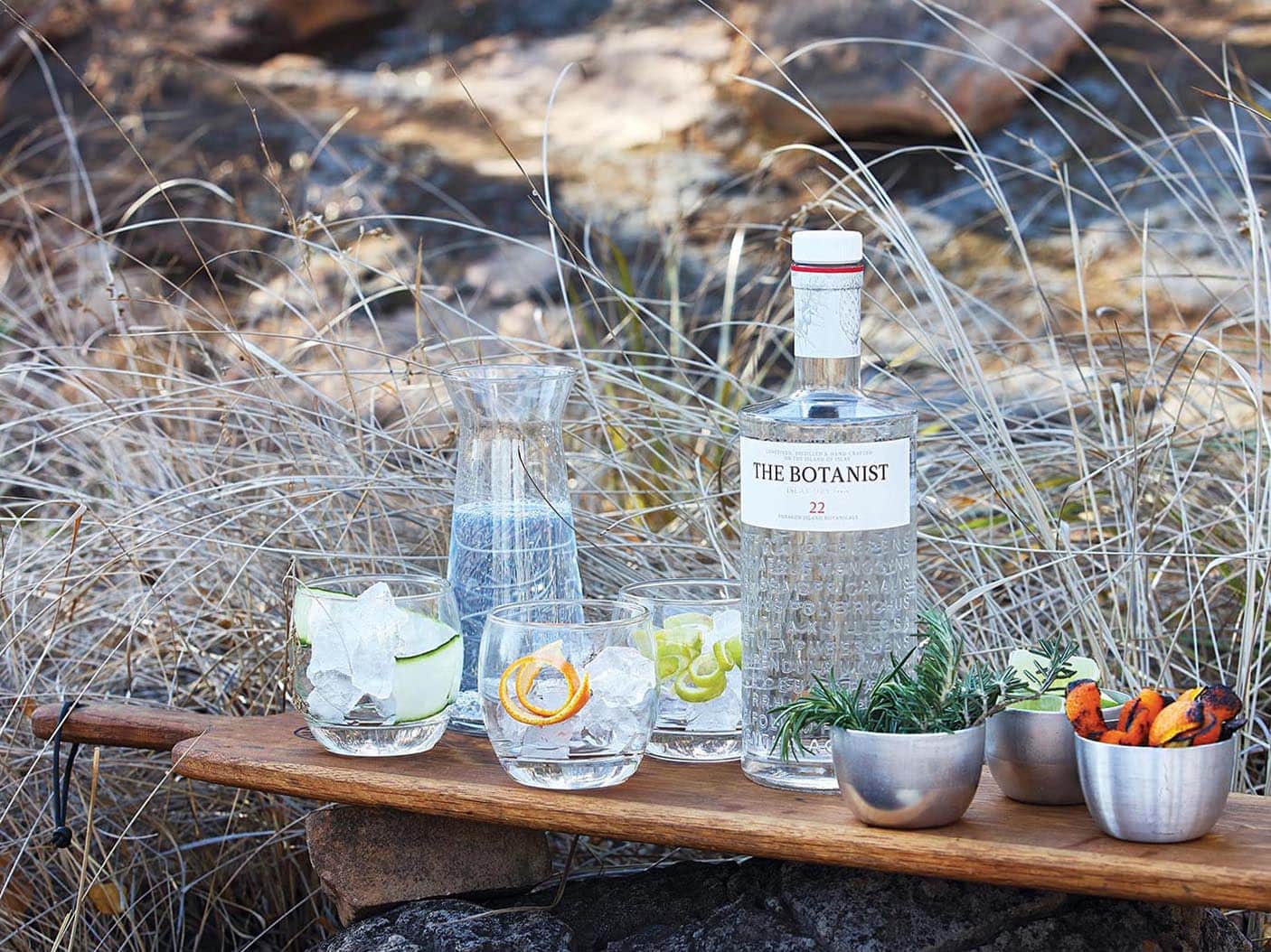 Drinking glasses and a bottle of The Botanist gin outdoors on a serving board. Photo by Elsa Young Photography. Drinking glasses and a bottle of The Botanist gin outdoors on a serving board. Photo by Elsa Young Photography.