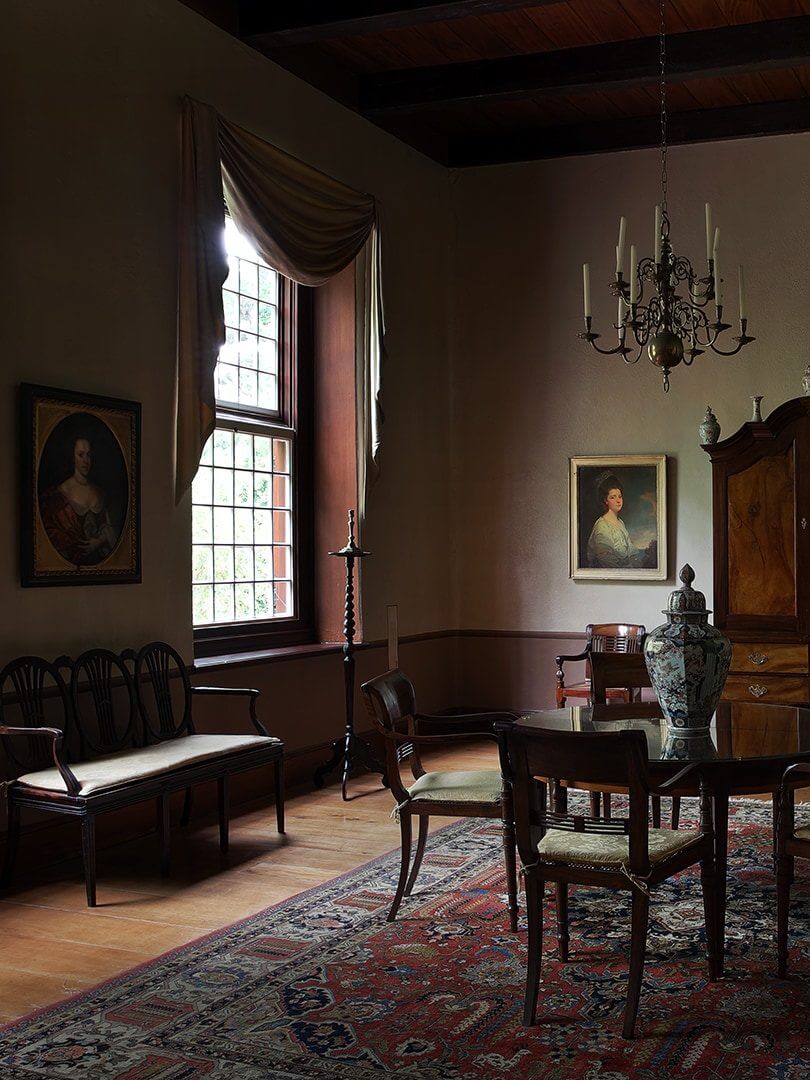 Beautiful, moody interior of a building at Vergelegen Wine Estate with massive sash windows and antiques. Photo by Elsa Young. Beautiful, moody interior of a building at Vergelegen Wine Estate with massive sash windows and antiques. Photo by Elsa Young.