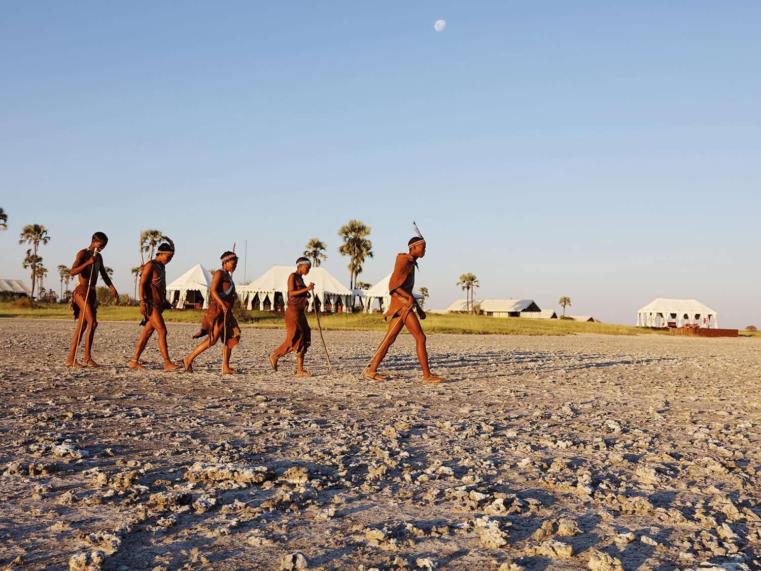 San tribespeople walking across sand in Botswana. Photo by Elsa Young. San tribespeople walking across sand in Botswana. Photo by Elsa Young.