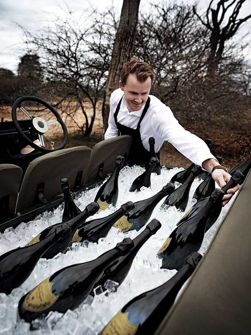 Man stacking the back seat of an open land rover with ice and dozens of bottles of Dom Perignon. Photo by Elsa Young. Man stacking the back seat of an open land rover with ice and dozens of bottles of Dom Perignon. Photo by Elsa Young.