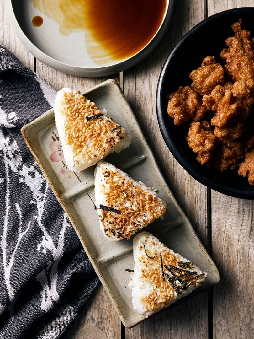 Triangular onigiri on a Japanese plate with dipping sauce. Photograph by Elsa Young. Triangular onigiri on a Japanese plate with dipping sauce. Photograph by Elsa Young.