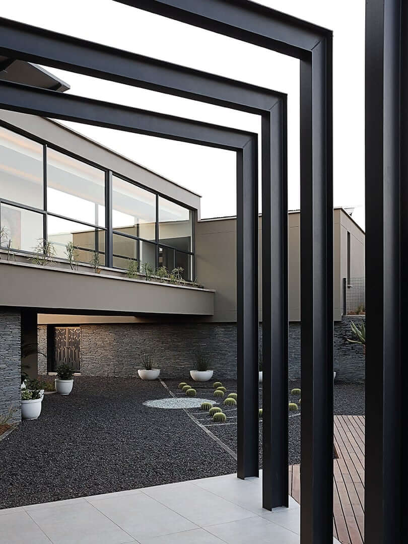 Modern house with cantilevered external black beams, photograph by Elsa Young